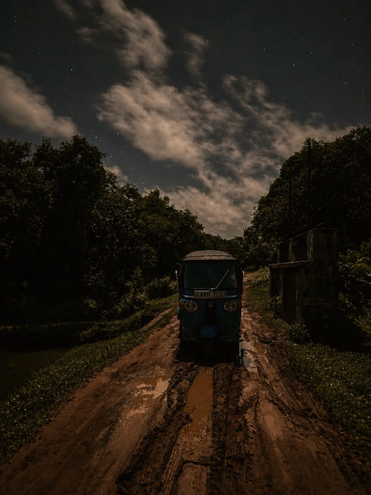 Tuk-tuk on a muddy back lane under a full moon